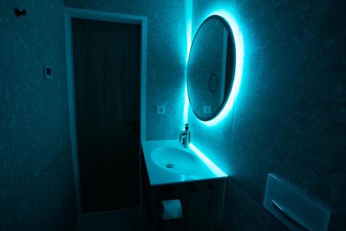 La salle de bains est pourvue d'un lavabo et d'un miroir éclairé bleu. dans l'établissement Emerald Valley Apartments, à Bovec