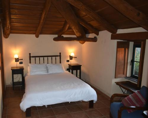 Un dormitorio con una cama con sábanas blancas y techos de madera. en CASA XAYMACA, en Samos