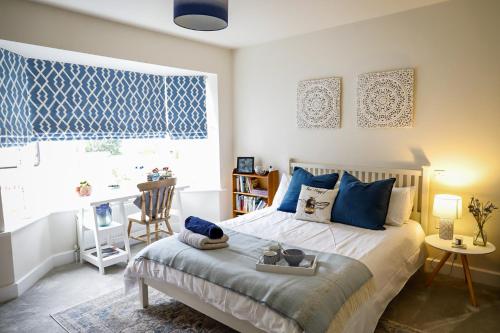 a bedroom with a bed with blue pillows and a window at The Ark 1 Christchurch in Holdenhurst