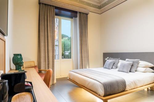 een slaapkamer met een bed, een tafel en een raam bij ETNEA Suite 270 in Catania