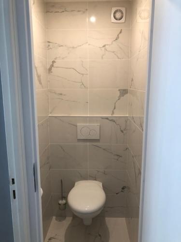 baño con azulejos de mármol y aseo blanco en 29 Promenade des Anglais en Niza