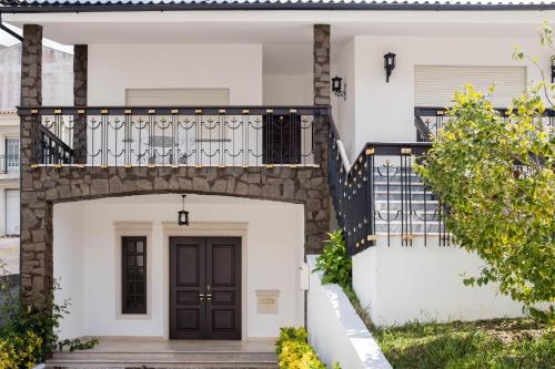 a white house with a black door and stairs at Moradia em Vilar dos Prazeres in Ourém