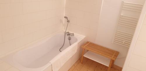 eine weiße Badewanne im Bad mit einer Holzbank in der Unterkunft La Maison près du ruisseau in Fenioux