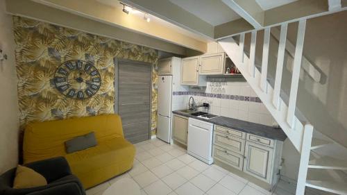 a kitchen with a yellow couch and a clock on the wall at Maison de plage in Frontignan