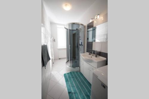 a white bathroom with a shower and a sink at Rozľahlý apartmán v centre Martina in Martin
