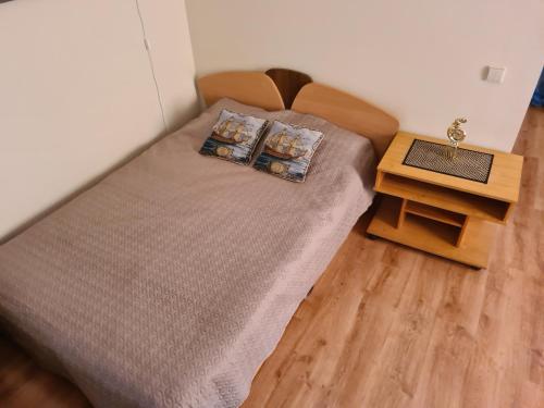 a bed with two pillows and a table in a room at Saulės apartamentai in Druskininkai