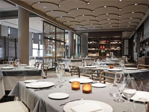 パルマにあるグランド ホテル デ ラ ヴィルのテーブルと椅子(白いテーブルリネン付)が備わるレストラン
