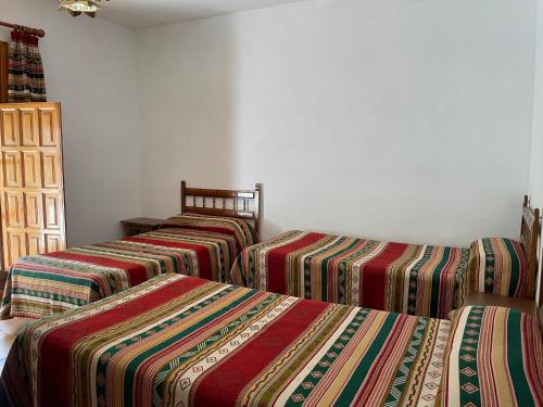 a group of three beds in a room at Hostal Rural Poqueira in Capileira