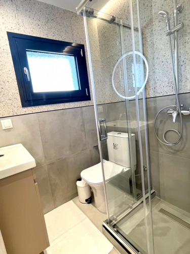 a bathroom with a shower and a toilet with a window at Agora LX Studios & Suites in Thessaloniki