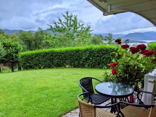 a patio with a table and chairs and red roses at Apartment with a view close to The Pulpit Rock in Jørpeland