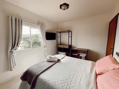 a bedroom with a white bed and a window at Pousada Guesthouse in Timbó