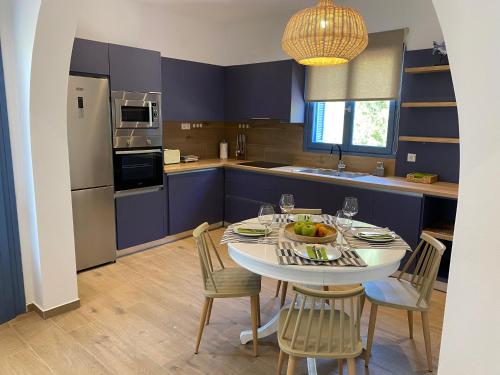 una cocina con mesa y sillas y una cocina con armarios morados. en Marine's luxury home, en Votsi