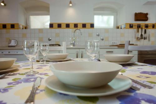 a table with bowls and plates and wine glasses on it at Riverside garden apartment Three Springs Tri Zvira in Plešce