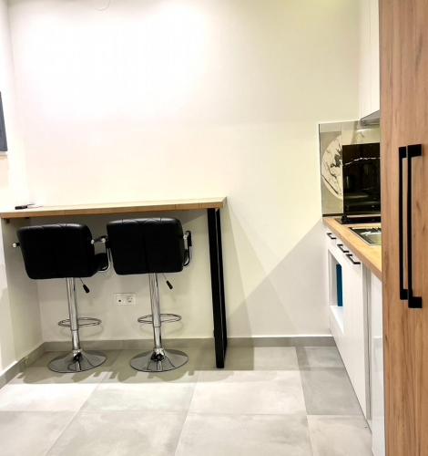 a kitchen with two bar stools in a room at Agora LX Studios & Suites in Thessaloniki