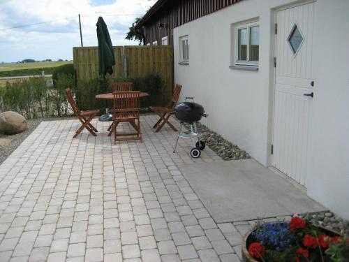 a patio with chairs and a table and a grill at Gårdsboende in Skårby