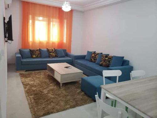 ein Wohnzimmer mit einem blauen Sofa und einem Tisch in der Unterkunft Zayatine wahat in El Aouina