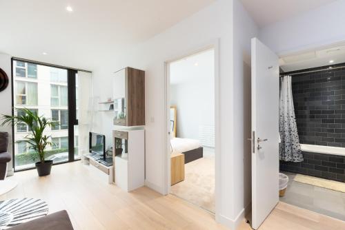 een kamer met een badkamer met een bed en een raam bij Austin David Apartments Royal Wharf in Londen