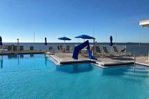 a swimming pool with blue water and chairs and umbrellas at 421-Fully renovated, WIFI, Pool, Amazing Views, Near BUCS Stadium in Tampa
