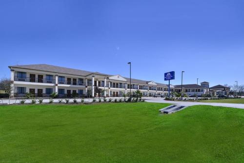 a large building with a green lawn in front of it at Americas Best Value Inn Cuero in Cuero