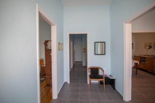 a hallway with a chair and a table in a room at ΑΝΑΚΑΙΝΙΣΜΕΝΗ ΜΟΝΟΚΑΤΟΙΚΙΑ στο κέντρο της πόλης με κήπο in Mesolongion