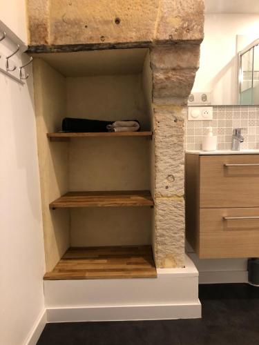 une cuisine avec des étagères en bois et un mur en pierre dans l'établissement Maison de pêcheur de 1820 au cœur du bourg - 3 étoiles, à Ouistreham