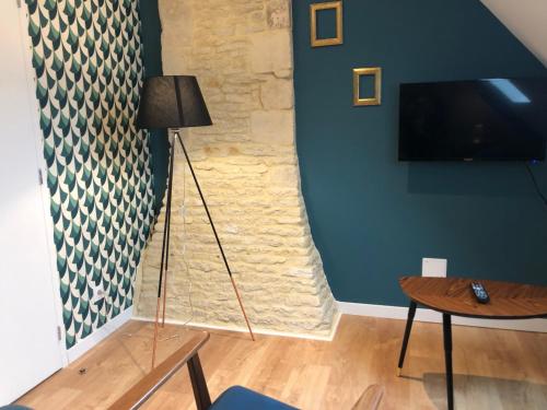 uma sala de estar com um candeeiro de chão e uma televisão em Maison de pêcheur de 1820 au cœur du bourg - 3 étoiles em Ouistreham