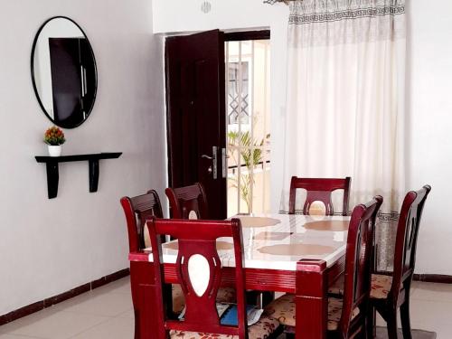 a dining room with a table and chairs and a mirror at Furnished Homes Nakuru with pool & GYM in Nakuru