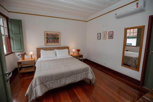 a bedroom with a bed and two tables with lamps at Pouso Jardim de Assis in Ouro Preto