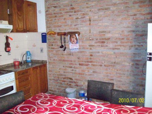 une cuisine avec un mur en briques et une photo d'un enfant dans l'établissement La Mima, à Capilla del Monte