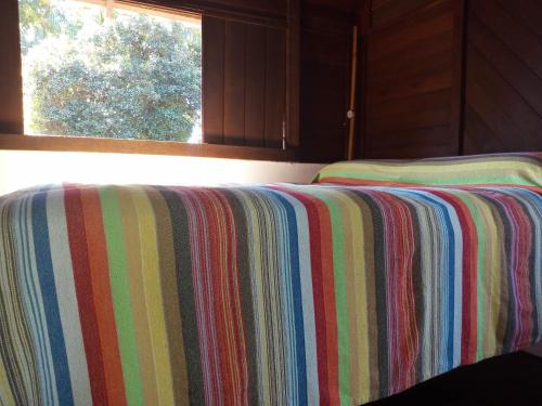 a striped blanket on a bed in a room with a window at Pousada Cachoeira in Abraão
