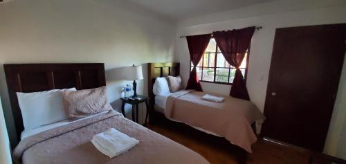 a hotel room with two beds and a window at Hotel & Restaurant Fleur de Lis in Concepción de Ataco