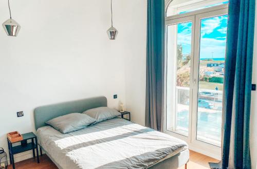 une chambre avec un lit et une grande fenêtre dans l'établissement La Maison Mickael, à Marseille