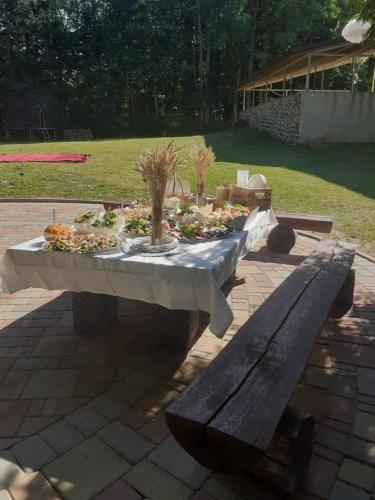 a table with a white table cloth and a bench at Viesu nams Vizbulītes in Talsi