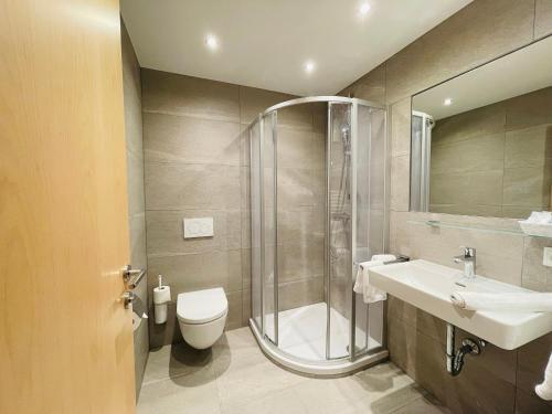 a bathroom with a shower and a toilet and a sink at Hotel Garni Burger in Sankt Jakob in Defereggen