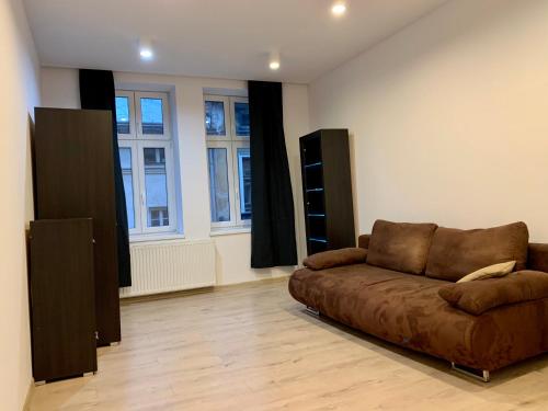 a living room with a brown couch and windows at Felicjanek Apartment in Krakow