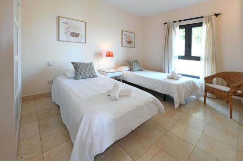 a room with two beds and a chair and a window at Salobre Morro Golf 1 in Salobre