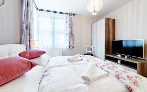 een slaapkamer met een groot wit bed en een flatscreen-tv bij Apartament przy stoku z ogrodem i tarasem - Pod Karpatką Residence Karpacz in Karpacz