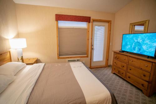 a bedroom with a bed and a flat screen tv at Banff Woods lodge in Canmore