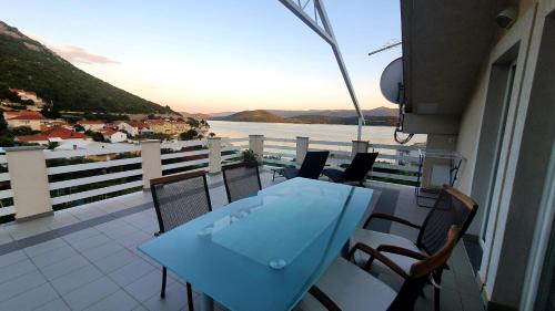 a table and chairs on a balcony with a view of the water at Apartmani Villa Delija Klek in Klek
