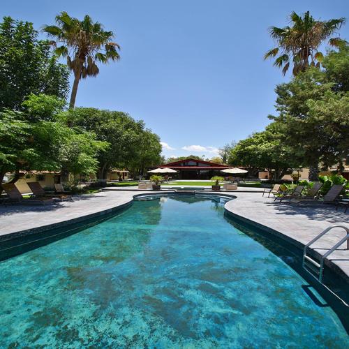 a large pool of blue water with chairs and trees at Real de Corralejo in San Miguel de Allende