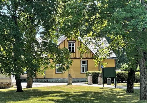 una casa amarilla con árboles delante de ella en Rüütli 1 - sea view apartement in Haapsalu Old Town en Haapsalu