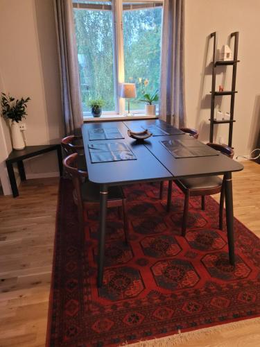 a dining room table and chairs on a rug at Lovely, spacious apartment with free parking in Sandviken