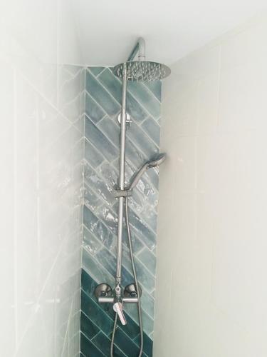 a shower in a bathroom with blue tiles at Ático Cádiz Suite in Cádiz