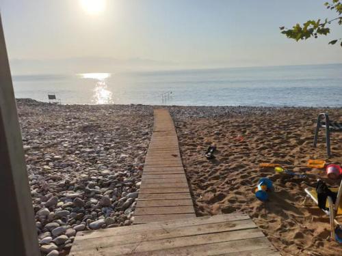 a wooden pathway on a rocky beach with the ocean at Agios Andreas Beach Villas in Áyios Andréas Messinias