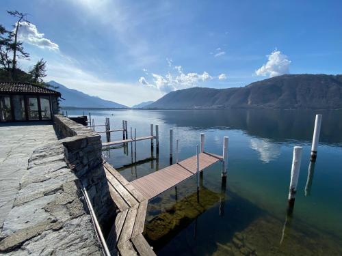 a dock on a lake with mountains in the background at Residenza Lago di Lugano in Bissone