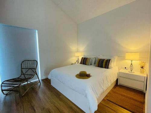 1 dormitorio con cama blanca, silla y lámpara en Casa do Patorrinho, en Arcos de Valdevez