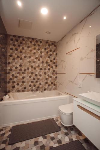 a bathroom with a tub and a toilet and a sink at Hotel Chicago in Shkodër