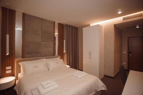 a bedroom with a white bed with two towels on it at Hotel Chicago in Shkodër