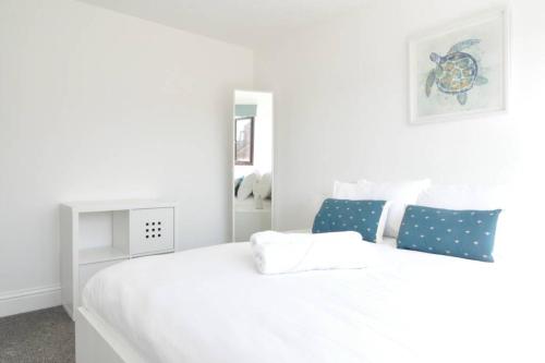a white bedroom with a large white bed with blue pillows at The Osprey - Newly Renovated House in Castle Gresley