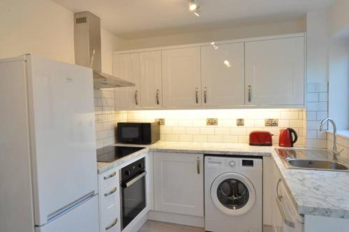 a kitchen with white cabinets and a washer at The Osprey - Newly Renovated House in Church Gresley